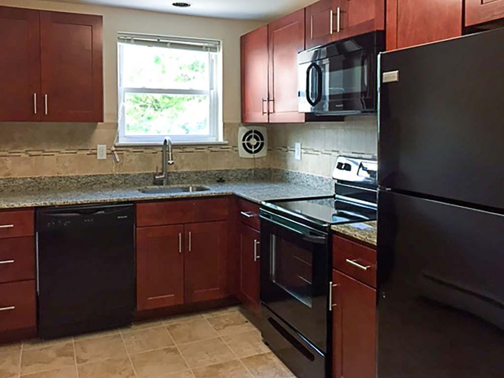 Kitchen with brown cabinets,black appliances, and granite countertops at Westgate Arms apartments