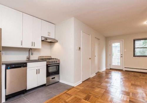 厨房有光滑的木地板，白色的橱柜，和不锈钢用具.